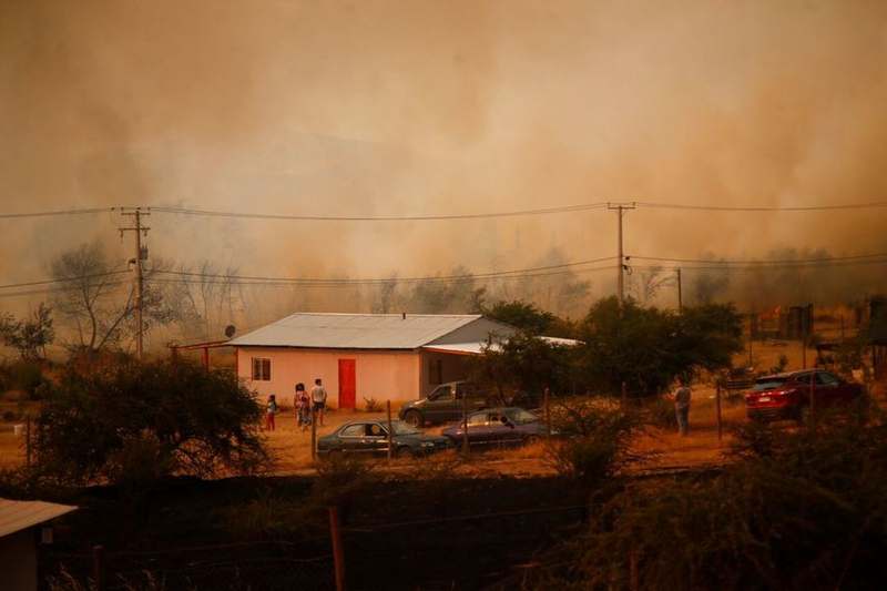 Incendio forestal avanzando cerca de una vivienda